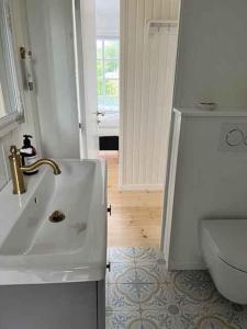 Baño blanco con lavabo y aseo en Bright And Cozy Summer Cottage On A Secluded Plot, en Kerteminde
