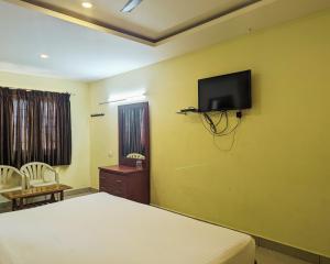 ein Schlafzimmer mit einem Bett und einem TV an der Wand in der Unterkunft Hotel Prakash Residency with EV Station in Tiruchchirāppalli