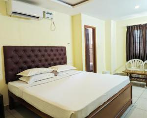 ein Schlafzimmer mit einem großen Bett mit einem braunen Kopfteil in der Unterkunft Hotel Prakash Residency with EV Station in Tiruchchirāppalli