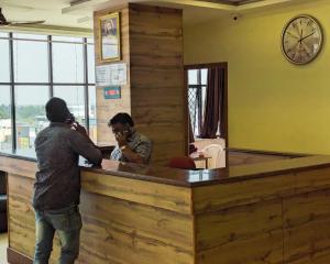 Ein Mann, der auf einem Handy an einer Bar spricht in der Unterkunft Hotel Prakash Residency with EV Station in Tiruchchirāppalli