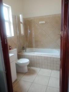 a bathroom with a toilet and a tub and a sink at Pine Tree Lodge PE in Port Elizabeth