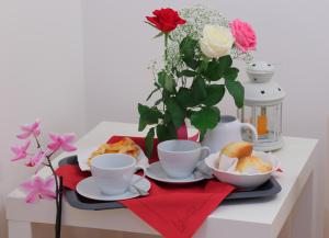 a table with cups and plates of food and flowers at La Terrazza sulla Valle in Agrigento