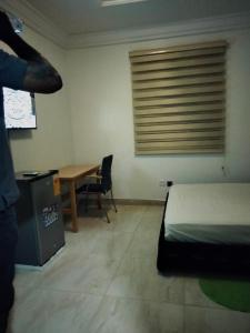 a bedroom with a bed and a desk and a table at Terra Santa Lodgings in Accra
