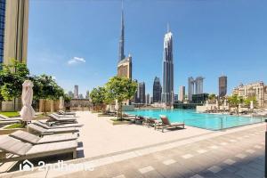 a swimming pool with lounge chairs and a city skyline at Direct Access to Dubai Mall, Downtown Views II T1 in Dubai