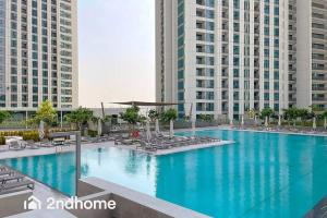 a large swimming pool with chairs and buildings at Direct Access to Dubai Mall, Downtown Views II T1 in Dubai