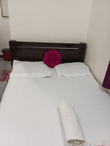 a large white bed with a red pillow on it at Mhatre Cottage Alibag Mani in Alibaug