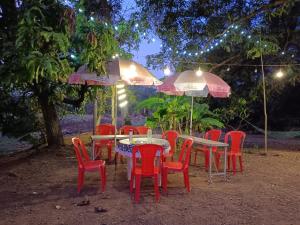 grupa stołów i krzeseł z parasolami w obiekcie Mhatre Cottage Alibag Mani w mieście Alibag