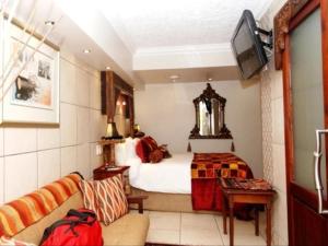 Habitación de hotel con cama y TV en Jane's Guesthouse, en Saldanha
