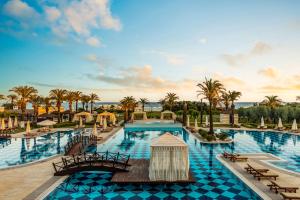 a resort with a large swimming pool with palm trees at Kempinski Hotel The Dome Belek in Belek