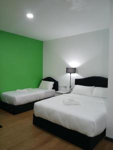 um quarto com duas camas e uma parede verde em TZ SATELLITE HOTEL, Kota Bharu em Kota Bharu