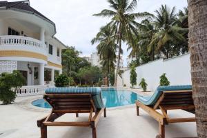 a villa with a swimming pool and two chairs at Tahira Villa in Diani Beach