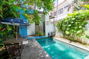 a house with a pool and a table and an umbrella at RedDoorz near Pantai Sanur Bali in Sanur