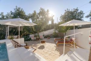 聖布拉什德阿爾波特爾的住宿－almóada - Eclectic Boutique Home，一个带两把遮阳伞和游泳池的庭院