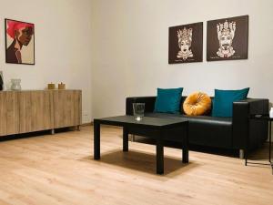 a living room with a black couch and a table at Arina Home -Aeroporto Fontanarossa- in Catania