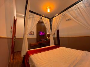 a bedroom with a canopy bed with a window at Hoàng Tây Hotel - Đồng Tháp in Ấp Hòa Lạc