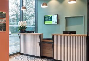 a lobby with two reception desks and a mirror at B&B HOTEL Versailles Rocquencourt in Rocquencourt