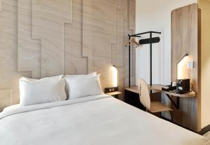 RocquencourtにあるB&B HOTEL Versailles Rocquencourtのベッドとデスクが備わるホテルルームです。