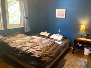 Cama en habitación con pared azul en Bellscabin Guesthouse en Karuizawa