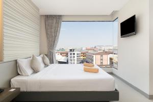 een slaapkamer met een bed en een groot raam bij Leenova Hotel in Bangkok