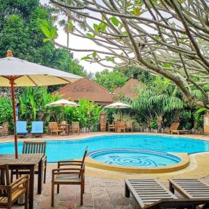 羅勇的住宿－Villa Bali Eco Resort, Rayong，一个带桌椅和遮阳伞的游泳池