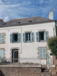 a white house with blue shutters and a fence at Studio 5 proche du port in Cancale