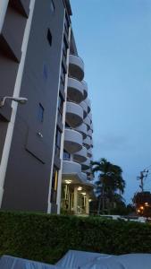 a tall white building with a palm tree in front of it at Garden Paradise in North Pattaya