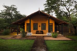 a small yellow house with a porch at Kumbukgaha Villa in Sigiriya