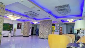 a lobby with purple lights on the ceilings and yellow chairs at Garden Hotel Muscat By Royal Titan Group in Muscat