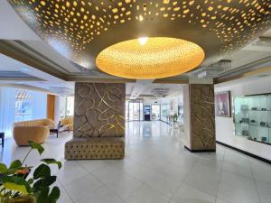 a lobby with a large chandelier in a building at Garden Hotel Muscat By Royal Titan Group in Muscat