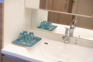 ein Waschbecken mit Spiegel und blauer Brille in der Unterkunft COSTA AKEBONO -Blanciera Naha Akebono Premist 1103- in Naha + 24 Fotos