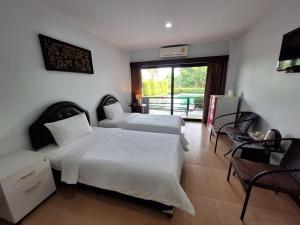 a hotel room with two beds and a balcony at Evergreen Resort Chanthaburi in Chanthaburi