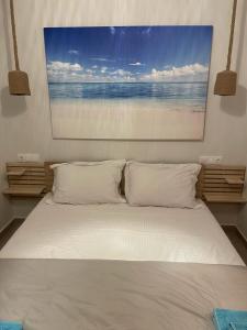 a white bed with two pillows and a painting on the wall at Sparti Apartment in Limenas