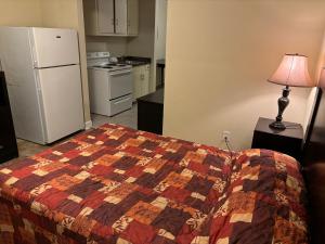 a bedroom with a bed and a kitchen with a refrigerator at Cook's Motel in Panama City Beach