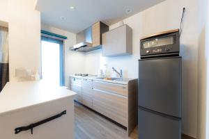 eine Küche mit weißen Schränken und einem schwarzen Gerät in der Unterkunft COSTA AKEBONO -Blanciera Naha Akebono Premist 1103- in Naha