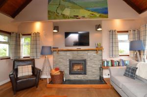 a living room with a fireplace and a tv at Alder Cottage in Blairmore