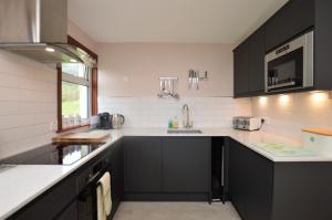 a kitchen with black cabinets and a sink at Alder Cottage in Blairmore