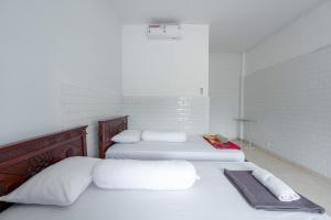 two beds in a white room with white walls at SDK Homestay Uluwatu in Uluwatu