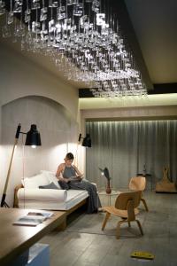 a person sitting on a bed under a chandelier at Trypiti Resort Blue Dream Palace and Hive Water Park in Limenaria