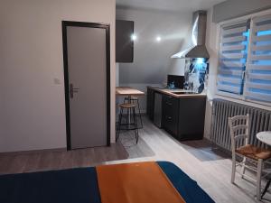 a room with a kitchen with a desk and a door at Studio Est proche centre ville in Loudéac