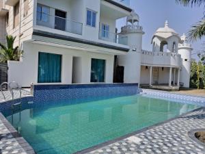 a villa with a swimming pool in front of a house at Ashoka Resort & Banquets in Begusarai