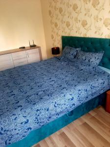 - un lit dans une chambre avec une couette bleue dans l'établissement Apartment on Dzenu Street, à Riga