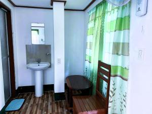 a bathroom with a sink and a shower curtain at Divinagracia Cottages in San Vicente