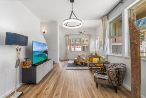 een woonkamer met witte muren en houten vloeren en een televisie bij @Marbella Lane - 7BR home w/ Mountain+Ocean Views in Waianae