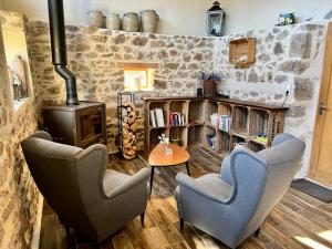 sala de estar con 2 sillas y estufa de leña en Moulin des Comtes - chambre des comtes, en Viverols
