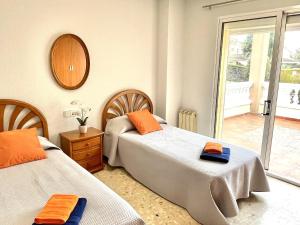 a bedroom with two beds with orange towels on them at APARTBEACH EL PINAR CON PISCINA y BARBACOA in Reus
