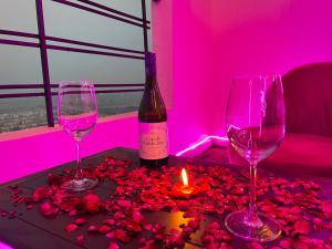 two wine glasses and a candle on a table with roses at Serene Stay India in Greater Noida