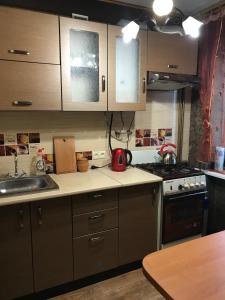 a kitchen with wooden cabinets and a red kettle on the counter at Затишна однокімнатна квартира 5 хв від Південного вокзалу in Kharkiv