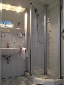 ein Bad mit einer Dusche und einem Waschbecken in der Unterkunft Hotel Villa Weststrand in Borkum