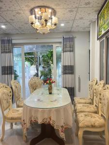 una sala da pranzo con tavolo, sedie e lampadario di Green Jungle Homestay - Phù Hợp Gia Đình Từ 10 - 15 Người Lớn & 5 Trẻ Em - Bãi Đậu Xe Ô Tô, Sân BBQ - Miễn Phí Sử Dụng Dịch Vụ Hồ Bơi Cách Homestay 3 Phút Đi Bộ - 7 Phút Đi Bộ Đến Biển - 5 Phút Đến Chợ Hải Sản Phú Thuỷ a Phan Thiet