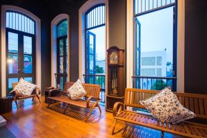 a room with three benches and a clock and windows at Little Nyonya Hotel in Phuket